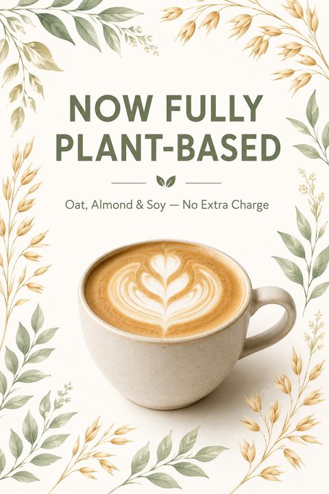 Flyer with a central photo of a latte with heart art in a ceramic mug. The text reads 'NOW FULLY PLANT-BASED' and 'Oat, Almond & Soy - No Extra Charge'. The edges are decorated with watercolor-style green leaves and golden oat stalks on a cream.